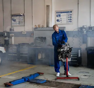 Mechanik pracujący przy silniku samochodowym w warsztacie